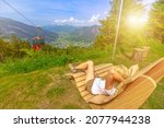 Woman relaxing at sunset on top of Brambruesch in Switzerland. Swiss cable car of Chur or Coira, antique town. Chur skyline in Grisons canton. Red cable car cabin from Chur to Kanzeli and Brambruesch.