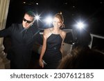 Small photo of Bodyguard escorting smiling celebrity arriving at event