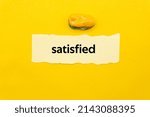 Small photo of satisfied.The word is written on a slip of paper. Emotional nouns, feeling words, emotional phrases. Positive or negative attitudes.