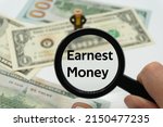 Small photo of Earnest Money.Magnifying glass showing the words.Background of banknotes and coins.basic concepts of finance.Business theme.Financial terms.