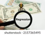 Small photo of Regression.Magnifying glass showing the words.Background of banknotes and coins.basic concepts of finance.Business theme.Financial terms.