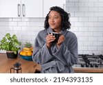 A young woman enjoys a moment waking up while she drinks coffee in the kitchen