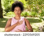 Young mutli-ethnic woman practices deep belly breathing, meditation in park