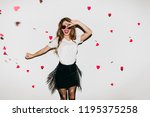 Small photo of Shapely happy girl jumping in studio decorated with hearts. European white woman expressing true positive emotions.
