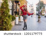 Magnificent caucasian girl in leather black shoes standing with legs crossed on pavement. Outdoor portrait of french female model in knee high boots posing in autumn day.