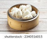 Small photo of steam honey glazed bbq pork buns with saucy filing served in dish isolated on wooden table top view hong kong food