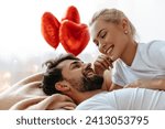 Small photo of Valentine's Day love and emotions shine as a young couple, lying together on a bed, look into each other's eyes and laugh, their connection and joy in this intimate, heartfelt moment