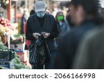 Small photo of Bucharest, Romania â€“ October 29, 2021: Man wearing a protective mask is counting his money during shopping in Obor Market, in Bucharest, Romania, 29 Oct 2021.