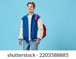 horizontal portrait of a handsome, joyful student guy with a red backpack on his shoulder, looking at the camera