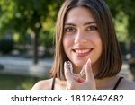 Small photo of Beautiful smiling Turkish woman is holding an invisalign bracer
