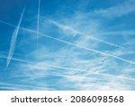 Airplane condensation trail or contrail with lines of clouds over blue sky background. High quality photo