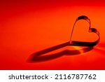 Small photo of Red, orange yellow, gradient background. Metal heart. Lights and shadows. Love, wedding, Valentine 's day, engagement, romance, infatuation, marriage, fidelity, devotion, happiness, hot love, warmth.