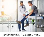 Small photo of Doctors do it for the health of it. Shot of a mature doctor examining his patient who is concerned about his knee.