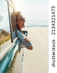 Small photo of Feeling free on the open road. Cropped shot of an attractive woman hanging out of a car window while enjoying a roadtrip.