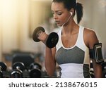 Small photo of She never skips a gym session. Shot of a young woman working out with dumbbells at the gym.