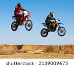Jumping in unison. Action shot of two dirt bikers mid-air.
