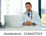 Small photo of My job is my calling. Portrait of a happy doctor using his laptop while sitting at his desk.