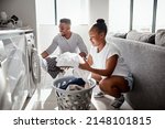 Small photo of Division of labour isnt just for the workplace. Shot of a happy young couple doing laundry together at home.