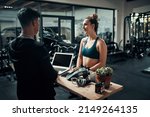 Small photo of Id like to sign up for premium membership please. Cropped shot of an attractive young sportswoman talking to a male fitness instructor at the reception of a gym.