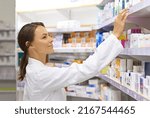 Small photo of Finding exactly what a customer needs. Shot of an attractive young pharmacist checking stock in an aisle.