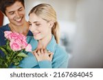 Small photo of Give her roses just because. Shot of an affectionate young man giving his beautiful young wife a bouquet of pink roses.
