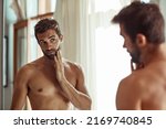 Keeping a close eye on any signs of aging. Shot of a shirtless man checking out his skin in the bathroom mirror.
