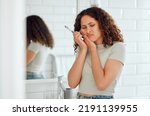 Toothache, pain and sensitive teeth with a woman brushing her teeth in a bathroom at home. Young female with a cavity suffering from discomfort during dental hygiene routine. Lady with a sore mouth