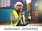 Small photo of Logistics, radio and a black man in shipping container yard with tablet. Industrial cargo area, happy transport worker talking on walkie talkie in safety gear and working for global freight industry.