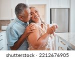 Love, laughing and elderly couple embrace in kitchen, having fun, talking and being silly together. Happy family, relax and retirement by senior man and woman enjoy conversation and relaxed lifestyle