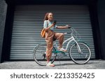 Bicycle, woman and phone in city feeling excited and happy about message while outdoor in summer with trendy look. Eco friendly transportation for carbon footprint female on a bike using 5g network