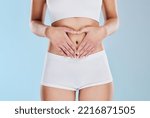 Small photo of Healthy stomach, heart and woman hands, wellness and gut health, body contouring and diet on studio blue background. Fitness model belly love, digestion and skincare, laser liposuction and abdomen