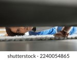 Woman, confused and couch looking for lost product in her home living room with doubt. Female, floor and checking under sofa for a missing item and searching her apartment or house in the carpet