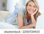 Small photo of Portrait of mature woman lying on sofa in living room, happiness and relaxing in comfort at home. Smile, lazy weekend time and happy woman in peace chilling on comfortable couch in apartment on break