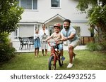 Small photo of Boy on bicycle learning with proud dad and happy family in their home garden outdoors. Smiling father teaching fun skill, helping and supporting his excited young son to ride, cycle and pedal a bike