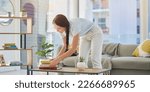 Small photo of Woman, cleaning and house with books in lounge, table and organize for housekeeping, tidy and order. Happy cleaner girl, book stack and living room for clean home, neat apartment or flat in New York