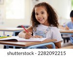 Learning, drawing and portrait of girl in classroom exam, education or studying with book. Preschool smile, development and happy kid or student coloring for creative art in notebook in kindergarten.