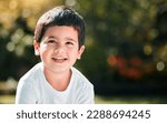 Small photo of Children, thinking and mockup with a boy in a park or garden, alone outdoor during a summer day. Kids, idea and smile with a happy male child outside in nature for freedom on a blurred background