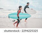 Small photo of We only things we chase, is waves. Shot of a man and his young son at the beach with their surfboards.