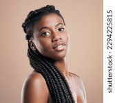 Small photo of My braids are my crown. Cropped portrait of an attractive young woman posing in studio against a brown background.