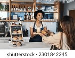 Small photo of Happy woman, barista and serving customer at cafe for service, payment or order on counter at coffee shop. African person, waitress or employee in small business restaurant helping client at checkout
