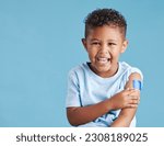 Portrait, happy and kid with plaster in studio isolated on a blue background mockup space. Face, smile and boy child with bandage after vaccine, injury or wound for healthcare, first aid and excited.