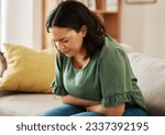 Small photo of Stomach pain, stress and woman on a sofa with pms, gas or bloating, constipation or menstrual nausea at home. Gut health, anxiety and female in living room with tummy ache, anxiety or endometriosis