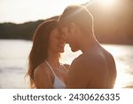 Love, sunset and couple on island for date on romantic anniversary vacation, adventure or holiday. Smile, bonding and young man and woman embracing with care by ocean on weekend trip together.