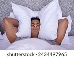Man, noise or insomnia in bedroom to rest, tired or cover ears with pillow for crisis of loud issue. Person, frustrated and mad for sound or sleep problem, anxiety and headache or stress in home