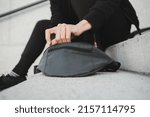Small photo of Person opening bum bag on the street wearing sporty clothing and sneakers
