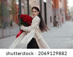 Happy woman holding bouquet of roses flowers in the city