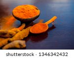 Small photo of Raw organic famous and essential spice i.e. Turmeric or haldi or Curcuma or Curcuma, saffron des Indes in a clay bowl along with its powder on brown colored wooden surface.