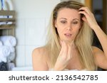 Small photo of Forty year old woman looking at a tuft of her hair in her hand appalled at the hair loss at her age