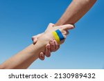 Small photo of Lend a hand help painted in ukrainian flag colors against blue sky. Stand with Ukraine