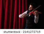 Man playing violin. Young man in theater playing violin. Violinist playing in front of his audience  Copyspace. background.